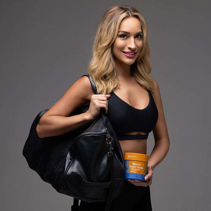 Fit woman holding GutSlim Probiotics Tummy Toner supplement container and gym bag for digestive health and belly fat reduction